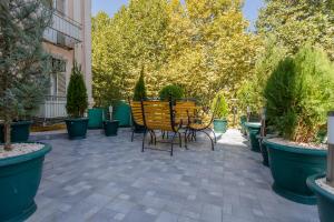 eine Terrasse mit einem Tisch, Stühlen und Topfpflanzen in der Unterkunft Mais Guest House in Tbilisi City