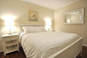 a bedroom with a white bed with two lamps and a mirror at Stylish Austin Condo in Austin