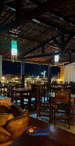 a restaurant with wooden tables and chairs at night at Pousada Tropicalia in Canoa Quebrada
