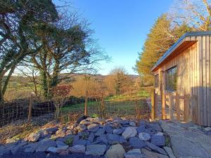 a small cabin with a fence and a pile of rocks at The Nest - Secluded Cabin with Panoramic Views in Gurteenulla
