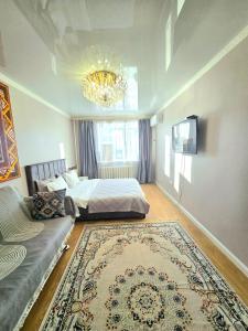 a bedroom with a bed and a couch and a chandelier at Аэропорт-Астана двухкомнатная in Astana