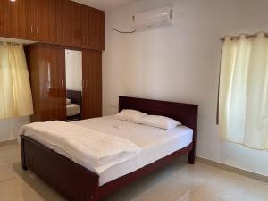 a bedroom with a large bed with white sheets at Santhosh Villa in Thanjāvūr