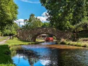 a stone bridge over a river with a boat at 1 Bed in Brecon oc-bn367 in Bwlch