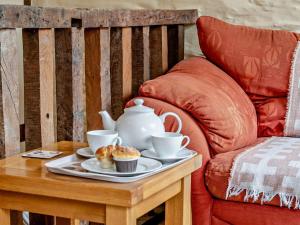 a tea pot and cups on a table next to a chair at 1 Bed in Brecon oc-bn367 in Bwlch