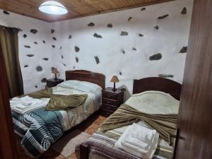 a bedroom with two beds and rocks on the wall at Casa da Queijaria in Faja Grande