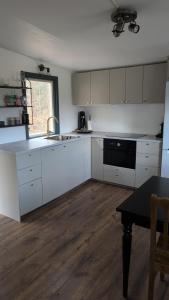 a kitchen with white cabinets and a sink and a table at Cosy cabin in Höör