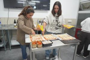 two women preparing pizzas on a table in a kitchen at CEAM Tabarca in Tabarca