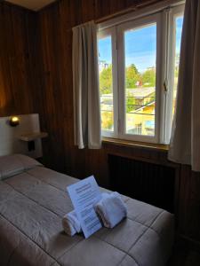 a bed in a room with a window with towels on it at Hotel Surprise Bariloche Centro con Desayuno y Restaurante in San Carlos de Bariloche