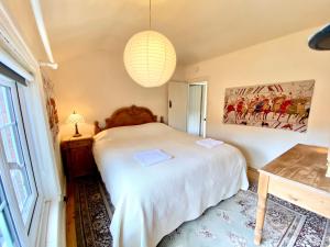 a bedroom with a white bed and a chandelier at Butterfly Cottage in Knowle