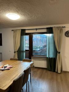 a dining room with a table and a large window at Piazzetta Montecampione in Pian Camuno