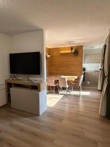 a living room with a television and a table with chairs at Piazzetta Montecampione in Pian Camuno