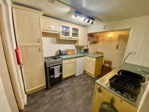 a small kitchen with white cabinets and a stove at Butterfly Cottage in Knowle