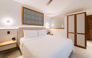 a white bedroom with a white bed and a window at Miamar in Manuel Antonio
