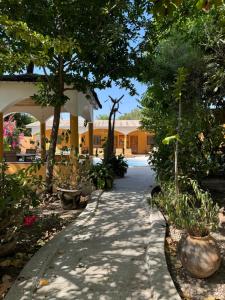 a walkway in a garden with trees and a building at Le Jardin du Saloum in Toubakouta