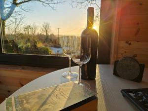 two wine glasses sitting on a table next to a bottle at The Perch - Romantic Cabin with Sunset Views in Gurteenulla +7 photos