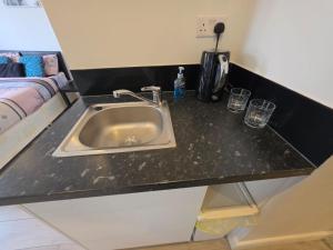 a kitchen counter with a sink and glasses on it at The Brigstock Nest in Thornton Heath