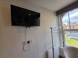 a flat screen tv hanging on a wall with a window at The Brigstock Nest in Thornton Heath