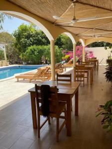 a patio with tables and chairs next to a pool at Le Jardin du Saloum in Toubakouta
