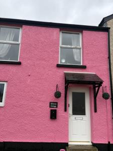 a pink house with a white door and windows at Roseus and Mimosa Cottages in Combe Martin