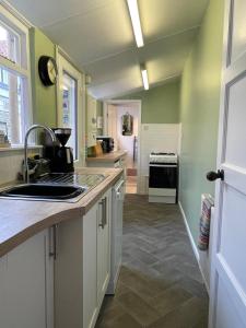 a kitchen with green walls and a sink at Charming Cottage and Beach Hut in Cromer