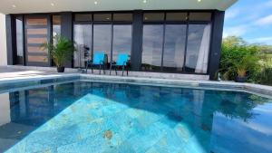 a swimming pool with blue chairs in front of a house at Ocean View House, Modern, Elegant with Pool in Coco +8 photos