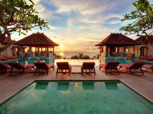 a resort with a swimming pool and tables and chairs at Mercure Kuta Bali in Kuta