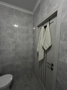 a bathroom with a toilet and a door with towels at Apartament modern cu dormitor separat si balcon panoramic in Căuşeni +10 photos