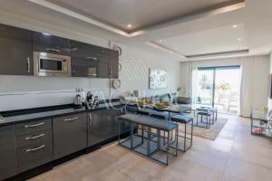 a kitchen with black cabinets and a table with chairs at Dassine View - Luxe - Agadir - 4 Px in Agadir +21 photos