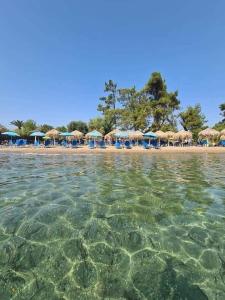 a beach with chairs and umbrellas and the water at Maria's House Kontokali in Kontokali