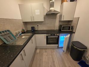 a small kitchen with a sink and a microwave at Brigstock 4 in Thornton Heath