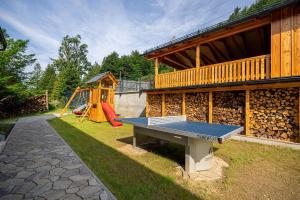 a ping pong table in front of a house with a playground at Wellness chata Kouty in Loučná nad Desnou