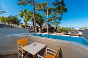 a patio with a table and chairs next to a swimming pool at Maistros Village Santorini - Anamar Collection in Karterados