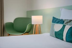 a bedroom with a bed with a lamp and green chairs at GuestReady - Beachside house with ocean view in Ponta Delgada