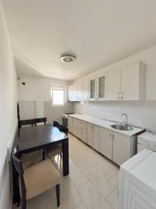 a kitchen with white cabinets and a table and a sink at Vega's in Tivat