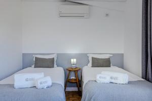 two beds in a room with white and gray at GuestReady - Beachside house with ocean view in Ponta Delgada