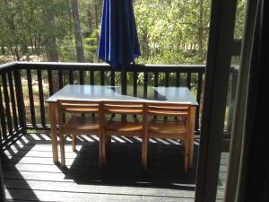 a table and chairs on a balcony with an umbrella at chalet dans les pins in Carcans