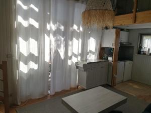 a kitchen with white curtains and a table in a room at chalet dans les pins in Carcans
