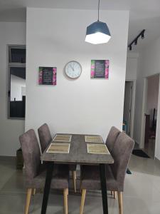 a dining room table with chairs and a clock on a wall at Aliffheight in Johor Bahru