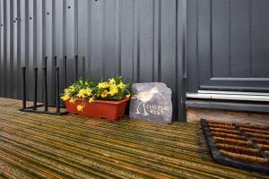 a pot of flowers and a sign next to a building at Host & Stay - Curlews Rest in Longridge