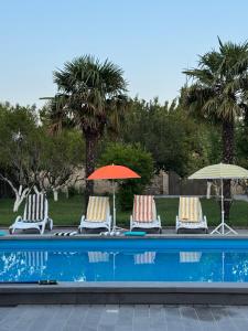 a group of chairs and umbrellas next to a swimming pool at Aisi Villa in Misakʼtsʼieli