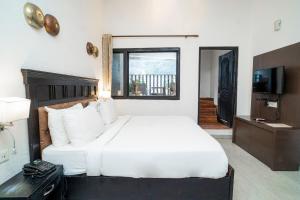 a bedroom with a white bed and a television at Hotel Ishan - A Ganges Riverside Retreat by Salvus in Rishīkesh +32 photos