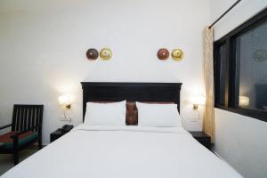 a bedroom with a large white bed and a chair at Hotel Ishan - A Ganges Riverside Retreat by Salvus in Rishīkesh