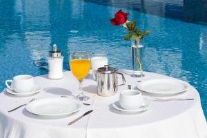 a table with plates and a glass of orange juice at Maistros Village Santorini - Anamar Collection in Karterados