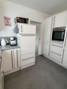 a kitchen with white cabinets and a white refrigerator at Entspannung am Wald in Wald-Michelbach +3 photos