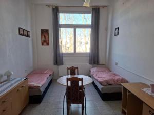 a room with two beds and a table and a window at Dům pro hosty in Přelouč