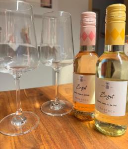 two bottles of wine and two wine glasses on a table at Ostseeperle Zingst, strandnahes 3-Zimmer Apartment in Zingst