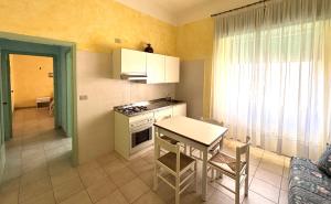 a kitchen with a table and a stove and a table and chairs at Smart Convenient Apartments Orosei in Orosei