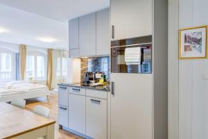 a kitchen with white cabinets and a refrigerator at HITrental Eisengasse Apartments in Lucerne