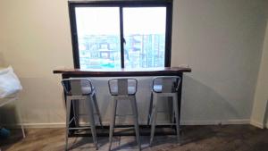 a bar with three stools in front of a window at SUP Hometel Phuket in Ban Thalat Choeng Thale