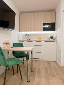 a kitchen with a table and green chairs at Studio Ariel in Veľký Meder